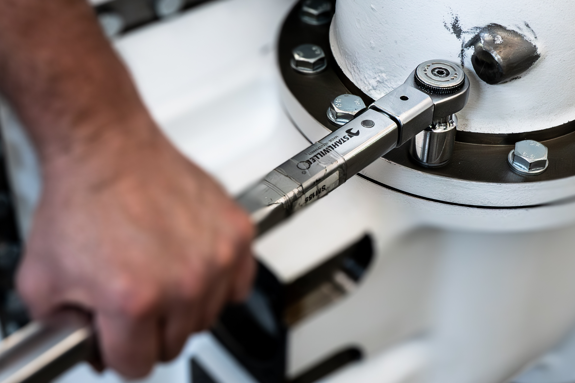 Technician torquing bolts on a flanged assembly with a calibrated torque wrench
